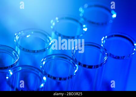 Fila di provette per test. Concetto di laboratorio medico o scientifico, goccioline di gocce di liquido con contagocce su sfondo blu, primo piano, fotografia micro Foto Stock