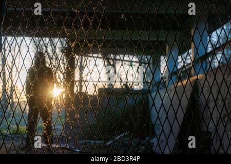 Una figura spaventosa incappucciata all'ingresso di un edificio abbandonato in rovina. Con il tramonto alle spalle Foto Stock