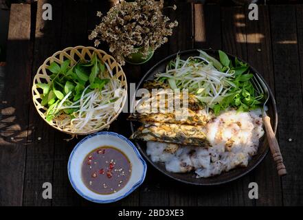 Cibo vegano vietnamita fatto in casa, piatto nero di rotolo di riso al vapore, pancake ripieni di pancake di riso arrotolato, funghi farciti, soia, delizioso piatto Foto Stock