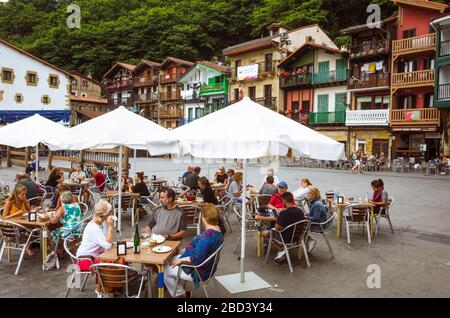 Pasajes, Gipuzkoa, Paesi Baschi, Spagna - 17 luglio 2019 : sia la gente del posto che i turisti siedono all'aperto in una taverna nella città vecchia di Pasajes de San Juan. Foto Stock
