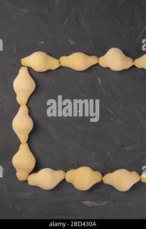 Conchiglie a forma di rettangolo con centro vuoto su fondo nero con tracciato di taglio. Concetto di prodotti di pasta Foto Stock