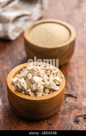 Blocchi di lievito fresco in ciotola su tavolo di legno. Foto Stock