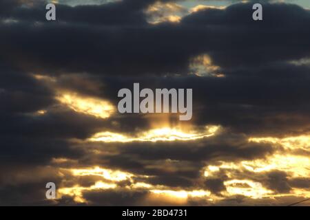 I raggi del sole passano attraverso le nuvole scure. Bellissimo cielo drammatico al tramonto o all'alba. Foto Stock