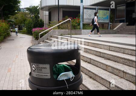 02.04.2020, Singapore, Repubblica di Singapore, Asia - UNA maschera facciale protetta scavata si trova all'interno di un cestino davanti ad una stazione della metropolitana. Foto Stock