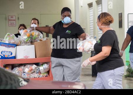 Florida, Stati Uniti. 06 aprile 2020: I lavoratori del servizio alimentare Juanita Fenn (a sinistra) e Charisa Beam del distretto scolastico di Palm Beach County forniscono i pasti mentre le famiglie si dirigono alla Village Academy Elementary School in mezzo alla pandemia globale del coronavirus COVID-19, lunedì 6 aprile 2020, a Delray Beach, Il distretto scolastico continua ad alimentare gli studenti, mentre le scuole sono chiuse in 35 siti in tutta la Palm Beach County. (Foto di IOS/Espa-Images) Foto Stock