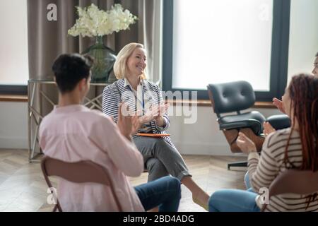 Psicologo biondo in una giacca grigia che guarda compiaciuto Foto Stock