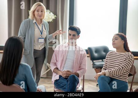 Psicologo biondo in una giacca grigia che guarda coinvolto Foto Stock