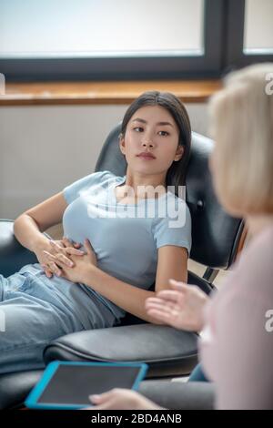 Giovane donna in una maglietta blu che ascolta con attenzione Foto Stock