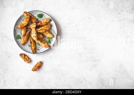 Zeppe di patate al forno con formaggio ed erbe - verdure biologiche fatte in casa vegetariane zeppe di patate snack pasto, vista dall'alto, spazio per le copie. Foto Stock