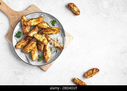 Zeppe di patate al forno con formaggio ed erbe - verdure biologiche fatte in casa vegetariane zeppe di patate snack pasto, vista dall'alto, spazio per le copie. Foto Stock