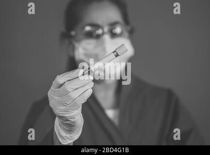 COVID-19. Medico o tecnico di laboratorio scienziato dei dispositivi di protezione individuale (DPI) che tiene in ospedale la provetta per il campione di sangue del paziente infetto. Coronavir Foto Stock