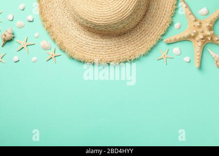 Cappello di paglia e stelle di pesce su sfondo alla menta, vista dall'alto Foto Stock