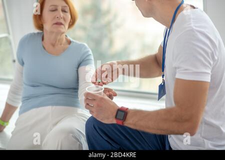 Medico giovane professionista che dà le pillole al suo paziente Foto Stock