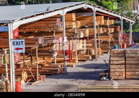 Magazzino di legno da cantiere aperto con scaffali di dimensioni dei prodotti tagliati in pile per i clienti. Foto Stock