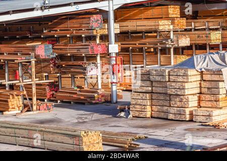 Magazzino di legno da cantiere aperto con scaffali di dimensioni dei prodotti tagliati in pile per i clienti. Foto Stock