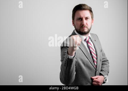 Ritratto di uomo d'affari che indossa abiti da lavoro mostrando pugno come essere pazzo isolato su sfondo grigio con spazio di pubblicità copia area Foto Stock