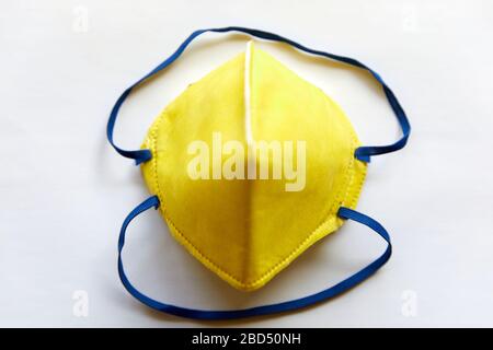 Vista dall'alto di una maschera gialla N95 isolata su un bianco per i medici e gli operatori sanitari. Ideale per la prevenzione del coronavirus Foto Stock