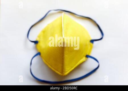 Vista dall'alto di una maschera gialla N95 isolata su sfondo bianco con fasce blu per respirare aria pulita Foto Stock