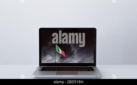 Apri un laptop con un'immagine significativa della bandiera italiana sotto un cielo tempestoso Foto Stock