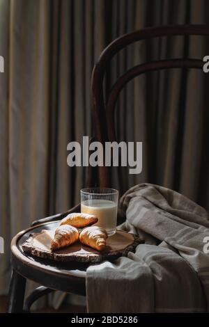 Scena mattutina con alcuni croissant e latte serviti sulla sedia vintage Foto Stock