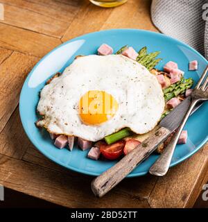 Colazione o pranzo con uova fritte, pane tostato, asparagi verdi, pomodori e pancetta Foto Stock