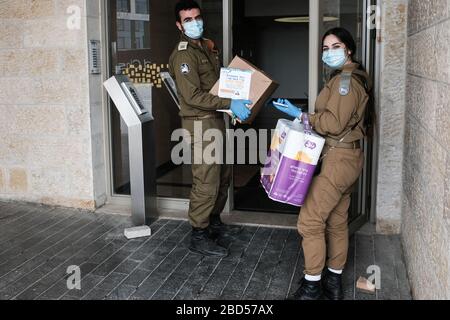 Gerusalemme, Israele. 7 Aprile 2020. Un ufficiale IDF e soldato del comando di fronte di casa entra in un edificio residenziale che consegna i pacchetti di cibo per la Pasqua ad uno dei 350,000 anziani in tutto il paese. Il Ministero della Difesa condivide le responsabilità per la gestione della crisi COVID-19. La Pasqua inizia al tramonto l'8 aprile 2020. Credit: NIR Alon/Alamy Live News Foto Stock