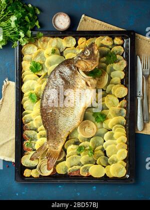 Carpa cotta, pesce intero dal forno con patate a fette su un grande vassoio piatto di pasta tradizionale Foto Stock