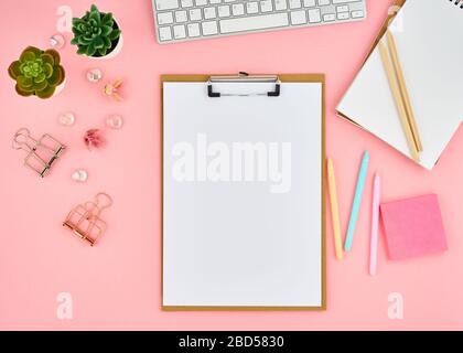 Pagina del blocco note vuota per il testo sul desktop rosa dell'ufficio. Vista dall'alto di un moderno e luminoso tavolo con notebook Foto Stock