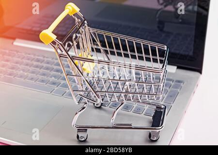Piccolo carrello da shopping in piedi sulla tastiera del computer portatile Foto Stock