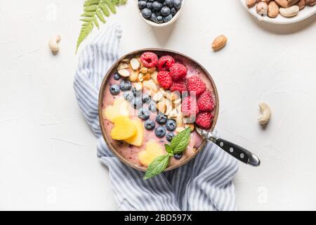 Frullato di banana e mirtillo su bianco. Colazione sana in una ciotola di cocco. Visualizza da. Cibo pulito, cibo vegetariano. Foto Stock