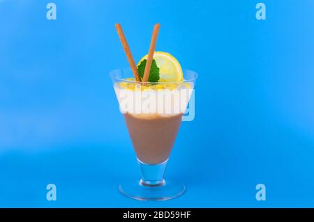 Budino di vaniglia al cioccolato in un bicchiere su sfondo azzurro. Spazio di copia. Foto Stock