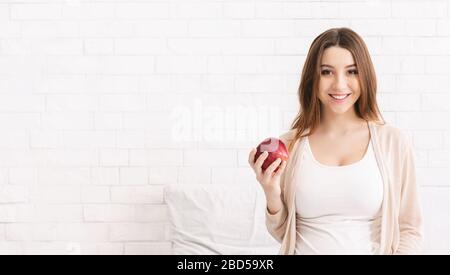 Giovane donna incinta godendo di mela fresca a letto Foto Stock