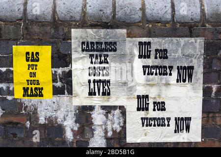 Poster in tempo di guerra intonacati su pareti in mattoni Foto Stock
