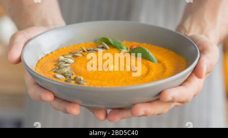 Lo chef ha preparato una zuppa di zucca calda e la porta nel piatto Foto Stock