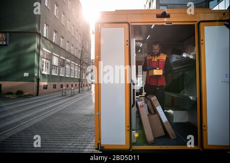 Gelsenkirchen, Germania. 7 aprile 2020. Nino Molldmann, il servizio di consegna pacchi di DHL, carica i pacchi dalla sua vettura a Gelsenkirchen-Buer. È uno degli "eroi della crisi corona" e lavora in una professione di importanza sistemica. Credit: Fabian Strauch/dpa/Alamy Live News Foto Stock