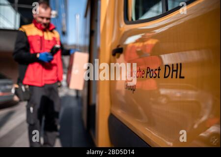 Gelsenkirchen, Germania. 7 aprile 2020. Nino Molldmann, il servizio di consegna pacchi di DHL, carica i pacchi dalla sua vettura a Gelsenkirchen-Buer. È uno degli "eroi della crisi corona" e lavora in una professione di importanza sistemica. Credit: Fabian Strauch/dpa/Alamy Live News Foto Stock