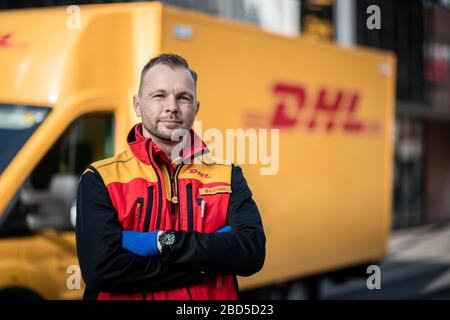 Gelsenkirchen, Germania. 7 aprile 2020. Nino Molldmann, uomo di consegna pacchi DHL, si trova di fronte alla sua auto a Gelsenkirchen-Buer. È uno degli "eroi della crisi corona" e lavora in una professione di importanza sistemica. Credit: Fabian Strauch/dpa/Alamy Live News Foto Stock