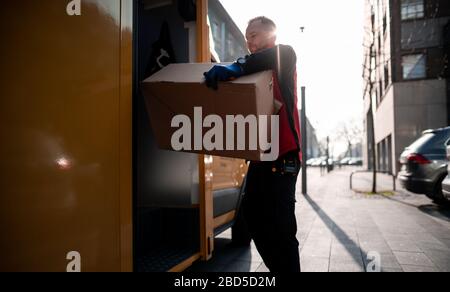 Gelsenkirchen, Germania. 7 aprile 2020. Nino Molldmann, il servizio di consegna pacchi di DHL, carica i pacchi dalla sua vettura a Gelsenkirchen-Buer. È uno degli "eroi della crisi corona" e lavora in una professione di importanza sistemica. Credit: Fabian Strauch/dpa/Alamy Live News Foto Stock