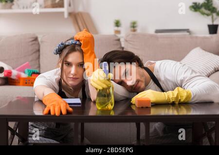 Procedura di pulizia. Coppia stanca appoggiata sul tavolo, esaurita dopo la rifinitura piatta Foto Stock