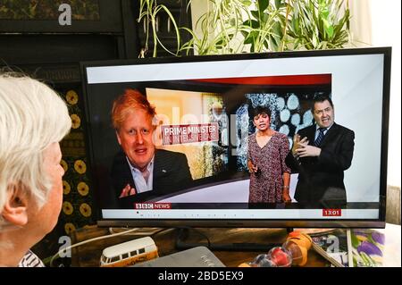 Donna anziana che guarda le notizie della TV di Boris Johnson che è ammesso a Intensive Care nel St Thomas Hospital di Londra con Covid-19, coronavirus. Foto Stock