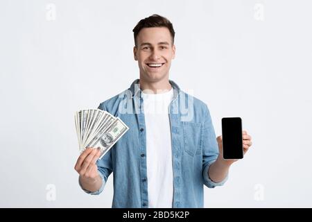 Uomo che tiene denaro e smartphone in mano Foto Stock