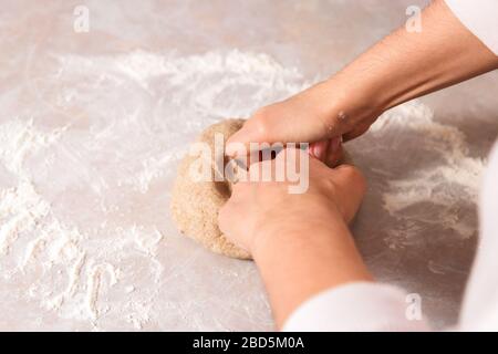 processo di cottura del pane di salute a casa. primo piano donna mani impastare l'impasto da farina di segale su marmo bancone in cucina luminosa Foto Stock