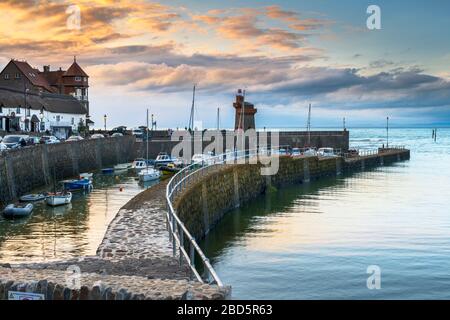 Come il sole che va giù i lampioni sfarfallio su attorno alla pittoresca North Devon porto di Lynmouth. Foto Stock