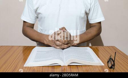 Un uomo che tiene le mani su un libro santo aperto. Concetto di preghiera. Foto Stock