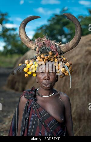 Con il suo piatto di labbra di argilla rimosso donna con frutta secca e corno di bestiame, tribù Mursi o gruppo etnico, Olikoru Village, Jenka, Etiopia. Foto Stock