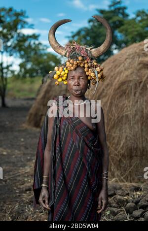 Con il suo piatto di labbra di argilla rimosso donna con frutta secca e corno di bestiame, tribù Mursi o gruppo etnico, Olikoru Village, Jenka, Etiopia. Foto Stock