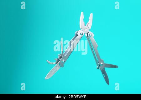 Lo strumento multifunzione multitool si trova su uno sfondo blu. Il concetto di un multi-utensile espanso con spazio libero. Foto Stock