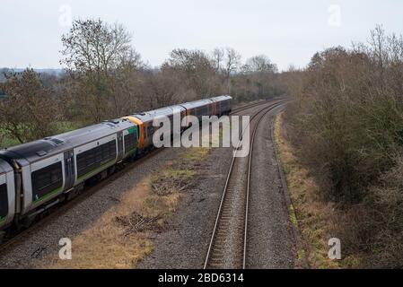Un treno per pendolari della West Midlands Railway viaggia verso una curva in alcuni binari del treno di campagna. Foto Stock