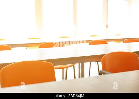 Una luminosa sala conferenze abbandonata con tavolo e sedie vuoti durante la pandemia del virus della corona. Foto Stock