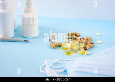 Maschere facciali protettive, pillole , sanitizzanti, gocce nasali e altri farmaci contro virus, coronavirus, freddo o influenza. Contenitori bianchi su sfondo azzurro. Mock-up. Foto Stock